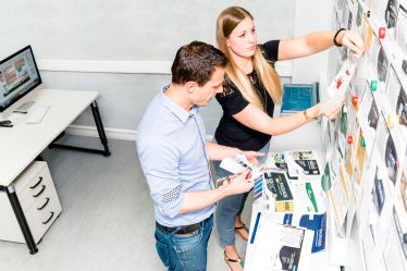 Zwei Personen arbeiten ein Marketingkonzept an einer Projektwand aus